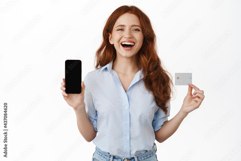 Happy bank client, shopping girl showing smartphone empty screen, credit card, laughing and smiling carefree, shop online, recommend mobile banking app, white background Happy bank client, shopping girl showing smartphone empty screen, credit card, laughing and smiling carefree, shop online, recommend mobile banking app, white background
