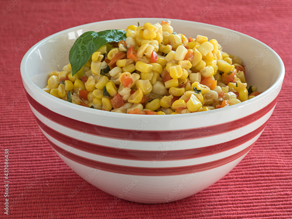 Corn and Red Pepper Side Dish in Serving Bowl on Red Corn and Red Pepper Side Dish in Serving Bowl on Red