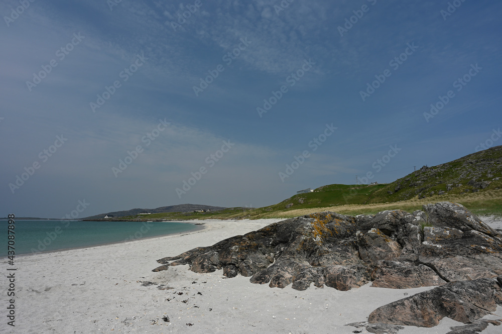 Prince's Beach or Prince's Strand on Eriskay, Outer Hebrides, Scotland. White sand, turquoise blue water, rocks, hills, blue sky and light cloud. Sunny day, no identifiable people. Copy space.