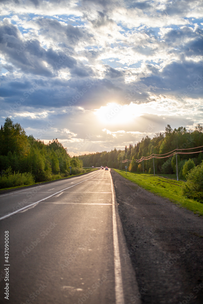 Country road with markings in the middle of the forest. Path and forward movement in the sun. Beautiful, green forest in the spring at sunset. Concept for success in the future goal and passing time Country road with markings in the middle of the forest. Path and forward movement in the sun. Beautiful, green forest in the spring at sunset. Concept for success in the future goal and passing time