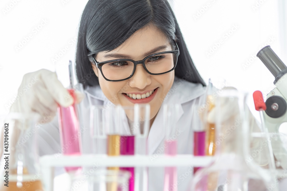 Young Asian scientist woman holding and looking at the chemical flasks in the laboratory Young Asian scientist woman holding and looking at the chemical flasks in the laboratory