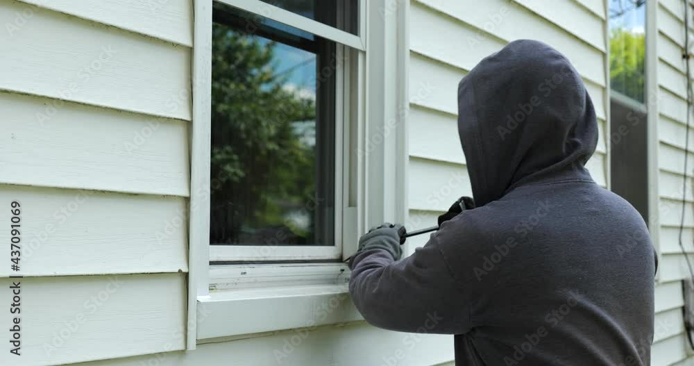 Burglar pries open a window with a crowbar and starts to climb into a home Burglar pries open a window with a crowbar and starts to climb into a home