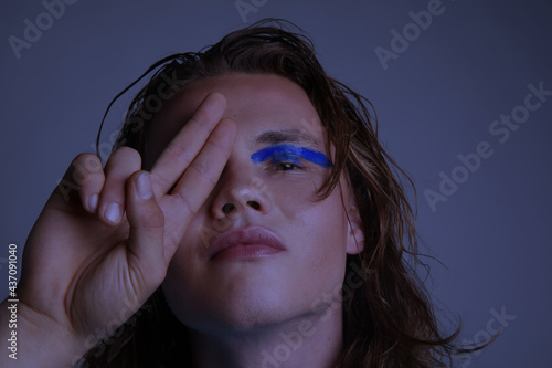 Close-up of young guy with creative make-up posing in the studio. Isolated. photo