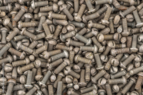 Dirty rusty pan head screw with a flat head screwdriver. Texture background of screws.