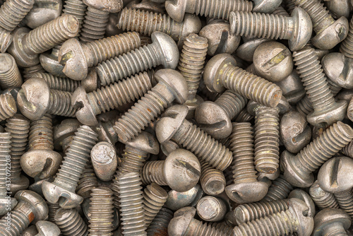 Dirty rusty pan head screw with a flat head screwdriver. Texture background of screws.