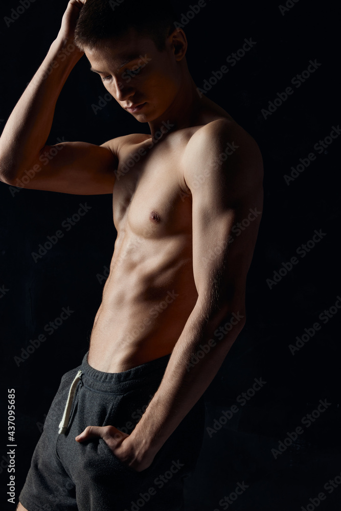 guy with a naked torso holds his hand near his face on a black background sports fitness guy with a naked torso holds his hand near his face on a black background sports fitness