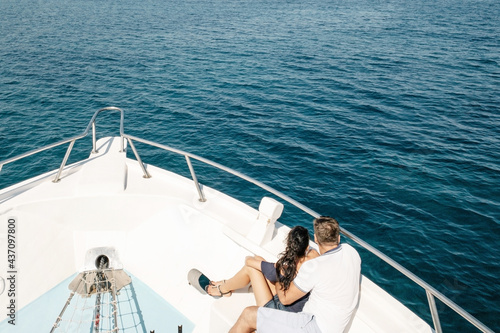 Romantic vacation and luxury travel. Young loving couple sitting on the sofa on the modern yacht deck. Sailing the sea. © KatrinaEra