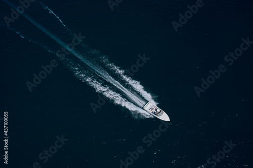 Motor boat in the sea. Travel - image. Drone view of a boat sailing. Top view of a white boat sailing to the blue sea. Large white boat fast movement on blue water aerial view. © Berg