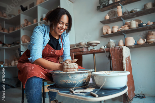 Foto Cheerful female potter making pottery in workshop