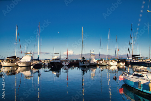 View of the lahaina harbor at dawn with setting moon and lanai in the distance © manuel