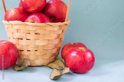 Close up view of red mature apples and basket full of apples with green leaves. Organic garden food
