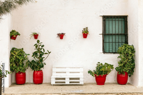 Fototapeta Naklejka Na Ścianę i Meble -  Beautiful white facade of a typical Andalusian house in Spain with plants in red clay pots