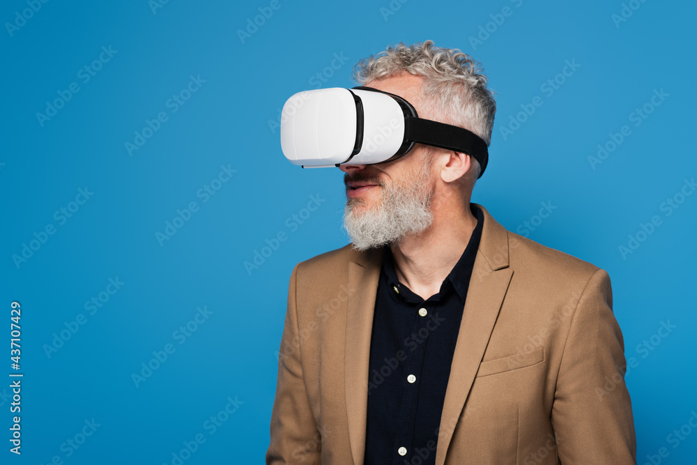 bearded middle aged man in vr headset isolated on blue bearded middle aged man in vr headset isolated on blue