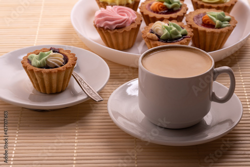 Morning aromatic coffee with colourful cupcakes with cream cakes on a white plate. Selective Focus