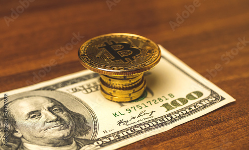 Bitcoin coin on a top of dollar money, concept of crupto currency new money, wooden table background