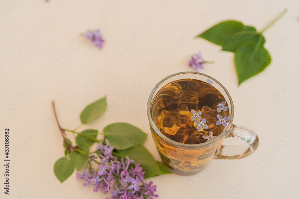 Lilac, purple flowers in a glass with tea on a yellow modern background. Concept, heat, quench your thirst, summer vacation, there is a place for text Lilac, purple flowers in a glass with tea on a yellow modern background. Concept, heat, quench your thirst, summer vacation, there is a place for text
