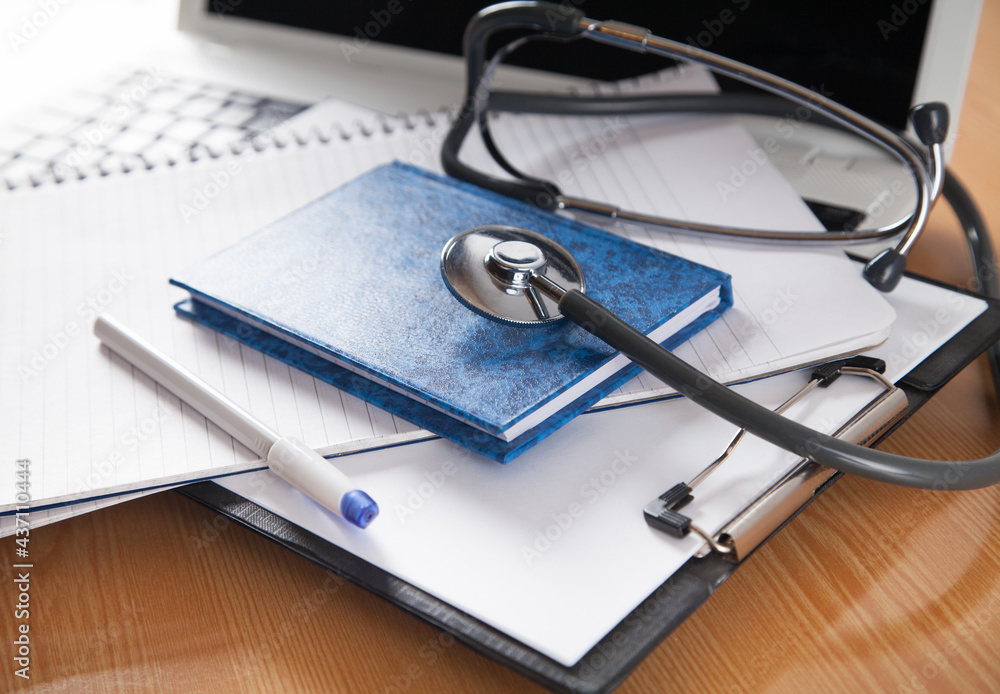 Stethoscope, computer, notebook and pen on wooden background. Doctors desk. Stethoscope, computer, notebook and pen on wooden background. Doctors desk.