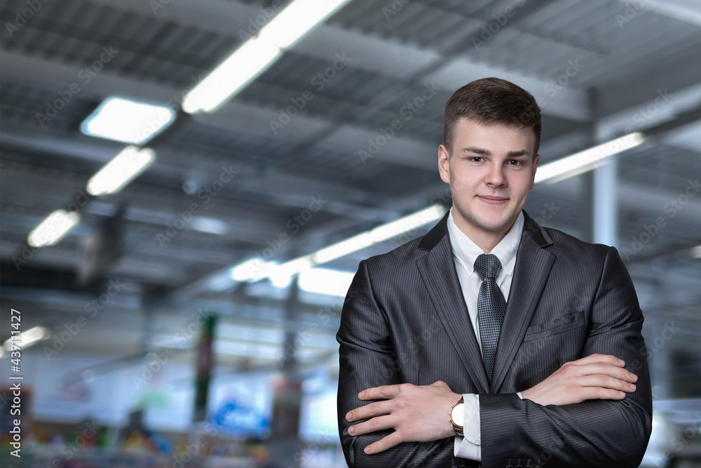 Businessman stands with arms crossed on blurred production background.