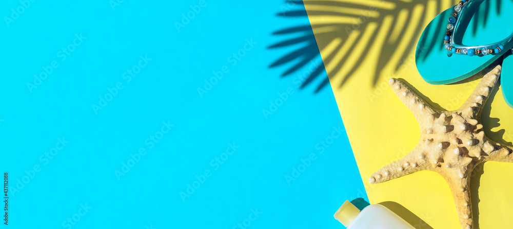 Dried starfish, sunscreen,blue beach flip-flops.and the shadow of a palm leaf on a yellow and blue background.Summer and travel concept.Copy space,flat lay,top view.
