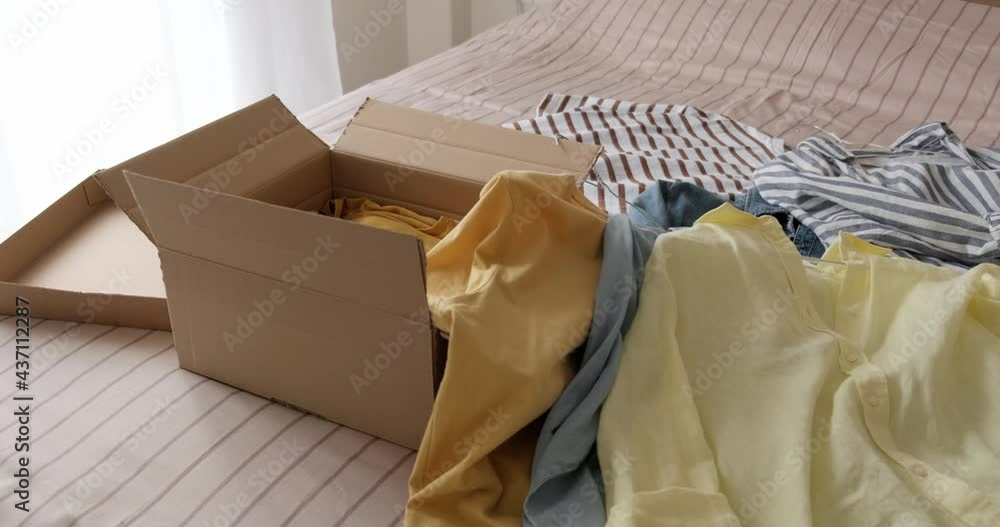 Bunch of used clothes being packed in carboard box, reusable clothing, concept of second hand resale or donation. 