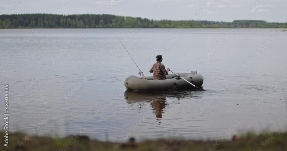 Beautiful cinematic shot. Girl fisherman rowing oars on lake an inflatable boat. Beautiful cinematic shot. Girl fisherman rowing oars on lake an inflatable boat.