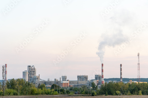 Factory chimneys against the gray autumn sky. Utopian landscape background. White toxic smoke is coming from a huge pipe. Pollution of the environment and nature. The collapse of civilization. © Pokoman