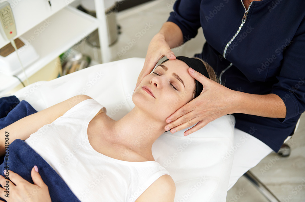 Beautician doing facial anti-aging lifting massage on woman face at spa clinic. Professional lymphatic drainage massage at spa center Beautician doing facial anti-aging lifting massage on woman face at spa clinic. Professional lymphatic drainage massage at spa center