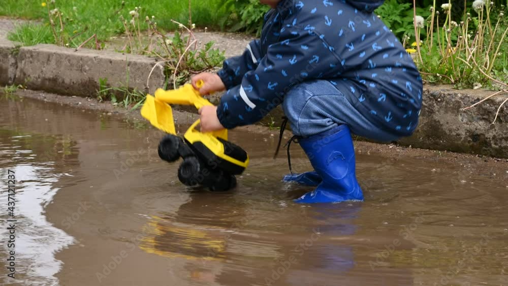 The child is playing in a large puddle. on the roadway The child is playing in a large puddle. on the roadway