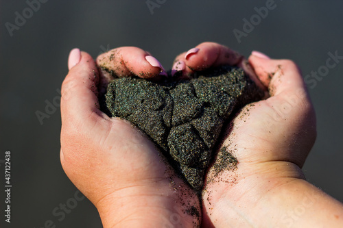 Black wet sand in white hands in the form of a heart, Pemuteran beach, north part of Bali island, Indonesia photo