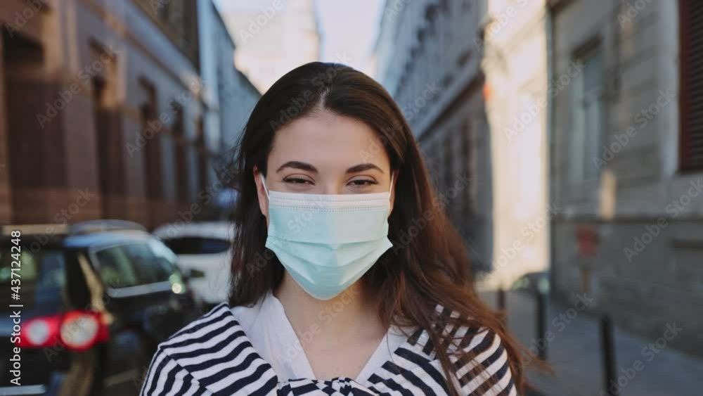 Portrait of the brunette caucasian girl wearing protective face mask on parking space at sunset. Outbreak of coronavirus COVID-19, pandemic and health care concept Portrait of the brunette caucasian girl wearing protective face mask on parking space at sunset. Outbreak of coronavirus COVID-19, pandemic and health care concept