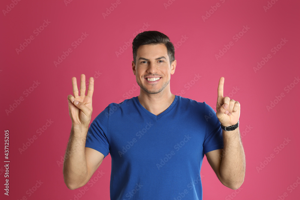Man showing number four with his hands on pink background Man showing number four with his hands on pink background