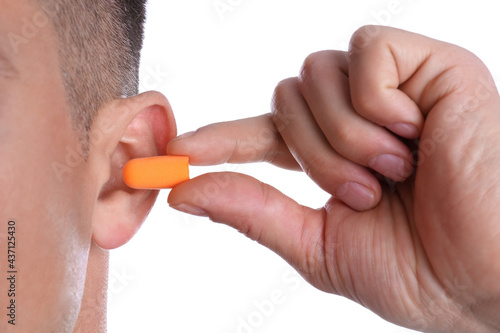 Bild auf Leinwand Man inserting foam ear plug on white background, closeup
