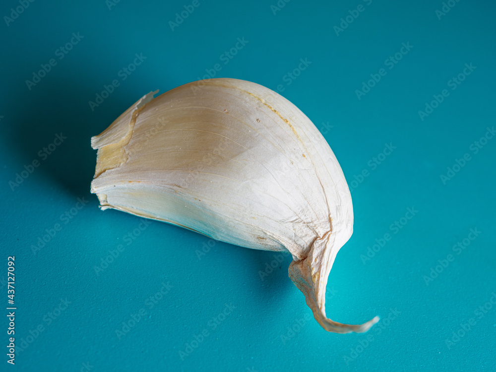 Fototapeta premium Top view of a garlic clove on a turquoise surface