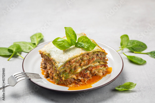 Homemade oven-baked green lasagna - Lasagne alla bolognese with spinach in the dough, ragu - meat sauce, bechamel and parmesan cheese. Italian food. Close-up. Horizontal image.