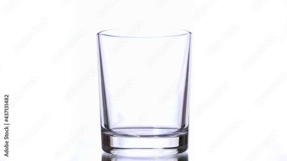 Slow motion macro still life of water poured in transparent glass isolated on white background Slow motion macro still life of water poured in transparent glass isolated on white background