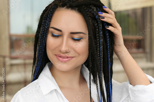 Fotografie Beautiful young woman with nose piercing and dreadlocks outdoors