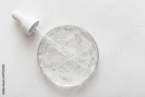 Close-up transparent cosmetic gel in glass petri dish with pipette on white background. Concept laboratory tests and research, making cosmetic. Copy space.