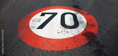 Top view of 70 km per hour, speed limit sign painted on dark asphalting road. Perspective concept. © Lalandrew