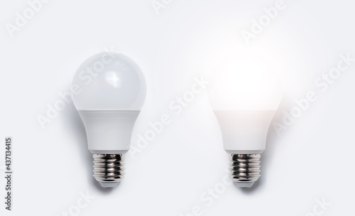 Close-up of two light bulbs with one glowing against white background. Business idea concept.
