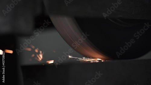 Swinging bench industrial grinding machine works on steel workpiece casting sparks on every pass of the grindstone - static camera, close up. High quality FullHD footage