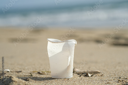 Isolated plastic cup discarded on sea coast ecosystem,nature waste pollution