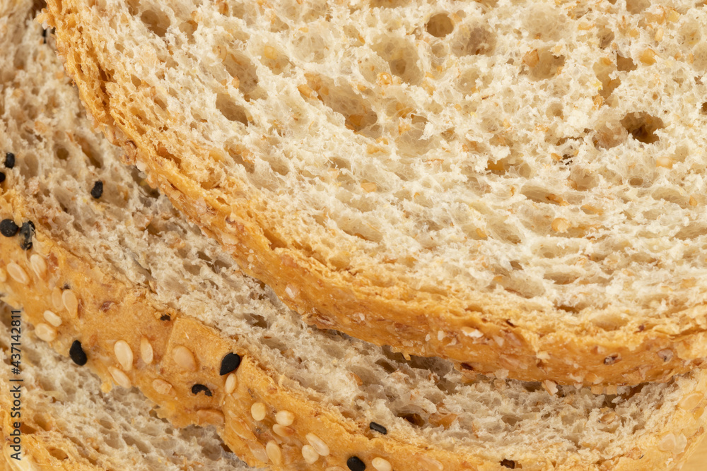 Close up of slices of whole wheat bread with oats, black and white sesame seeds.
