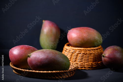 Fresh palmer mango in a basket on black background, Tropical fruit photo