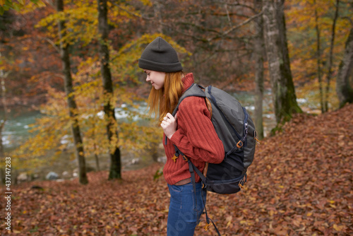 woman with backpack walking in the autumn park near the river in nature side view © SHOTPRIME STUDIO