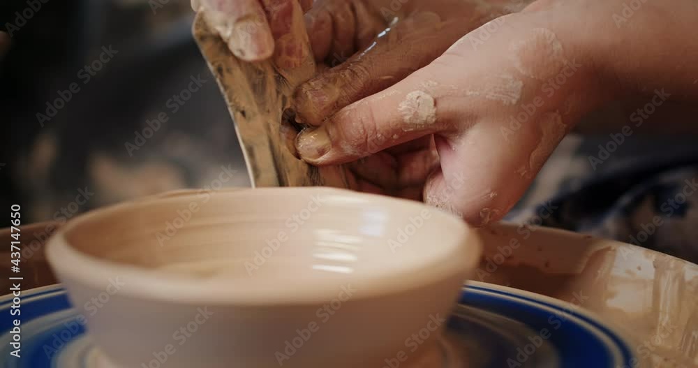 Teacher helping student to create clay bowl on pottery wheel Teacher helping student to create clay bowl on pottery wheel