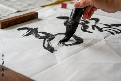 A calligrapher is writing calligraphy characters with a large brush, a close-up of the brush. Translation: The heights are too cold photo