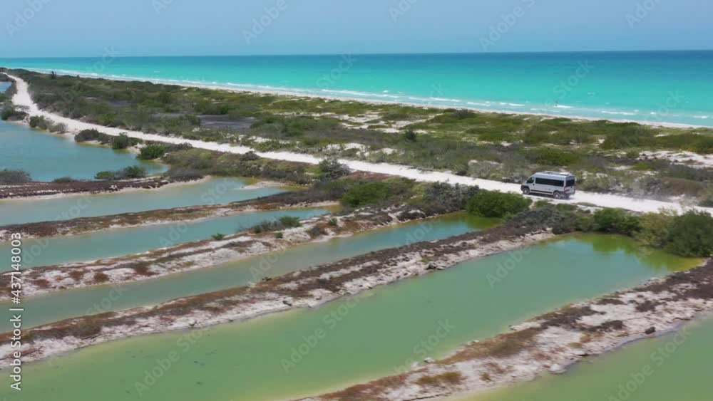 Aerial of camper van Driving white sand road with Caribbean ocean and salt lake view. Mexico, Rio Lagartos, aerial drone shot. Aerial of camper van Driving white sand road with Caribbean ocean and salt lake view. Mexico, Rio Lagartos, aerial drone shot.