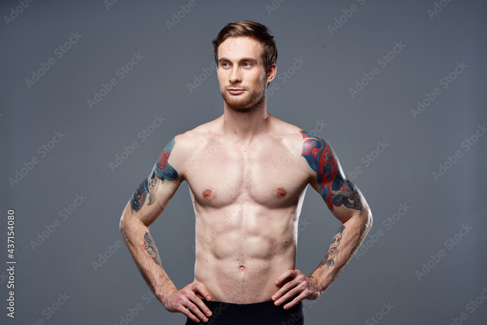 sporty man tattoos on his arms naked torso bodybuilder gray background