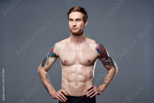 sporty man tattoos on his arms naked torso bodybuilder gray background