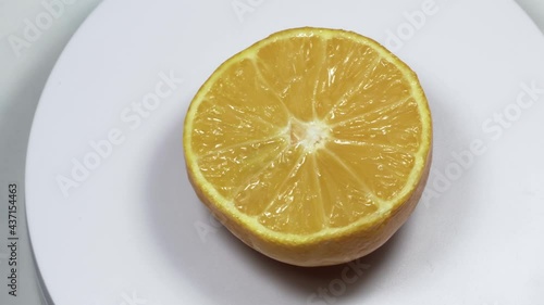 Rotating orange on a white plate and isolated background, juicy fresh yellow orange, vitamins and summer concept photo